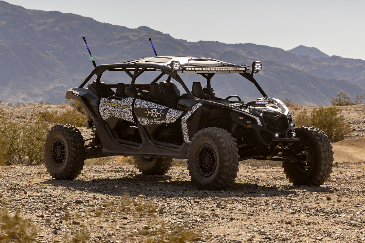 Black four seater off road vehicle with patterned side panels parked on desert terrain