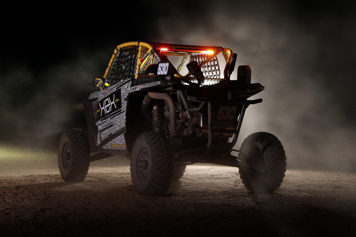 Rear view of a race UTV with number 530 and yellow roll cage in dusty conditions