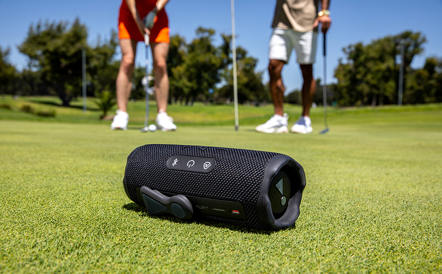 JBL Flip 7 portable Bluetooth speaker on a golf course