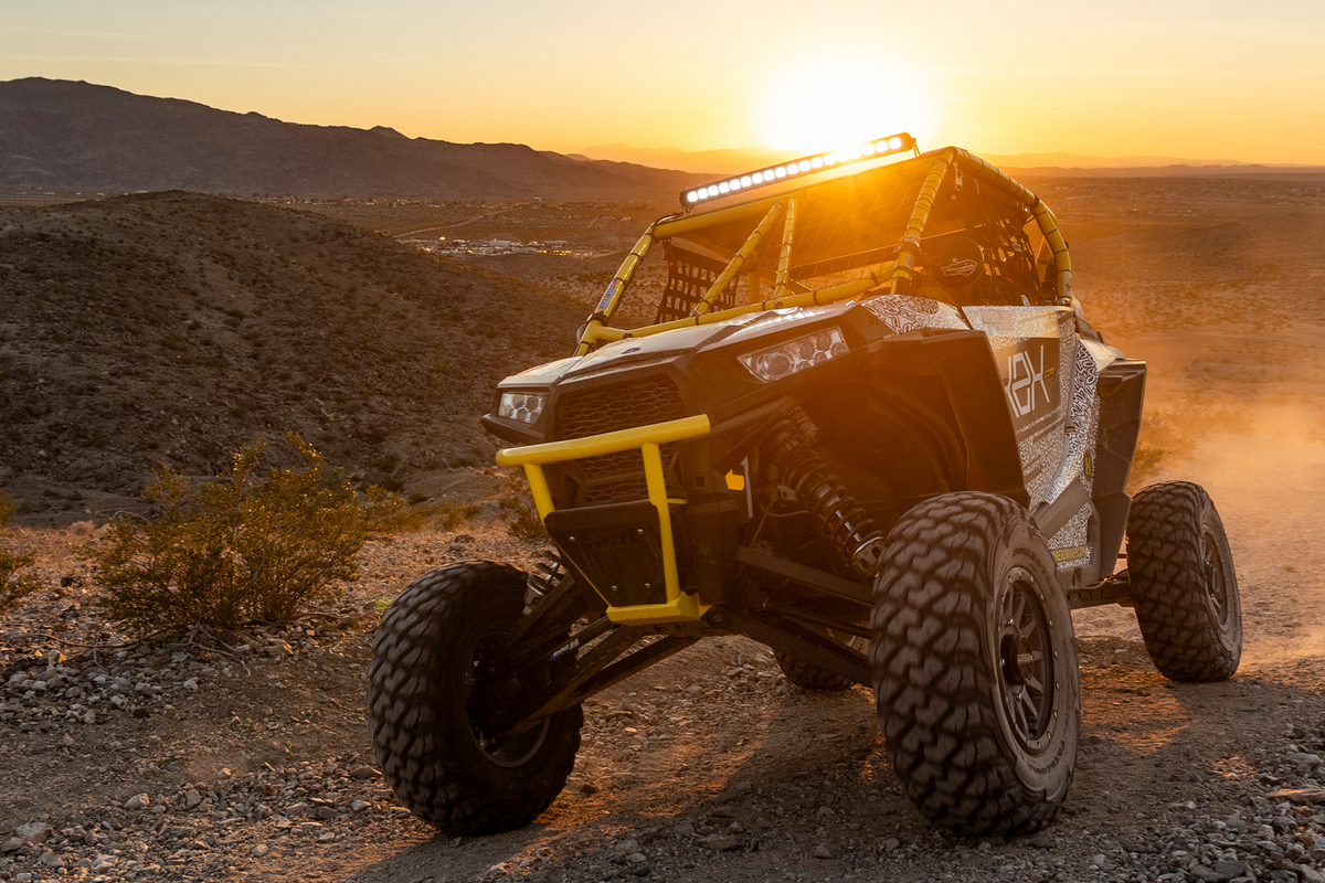 Polaris RZR off road vehicle with yellow roll cage on desert trail at sunset