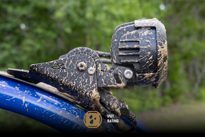 Mud covered off road LED light mounted on a blue vehicle frame with IP67 rating icon