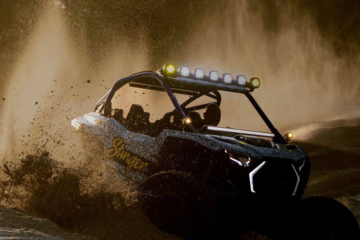 Stinger off road vehicle driving through dirt with roof mounted lights on