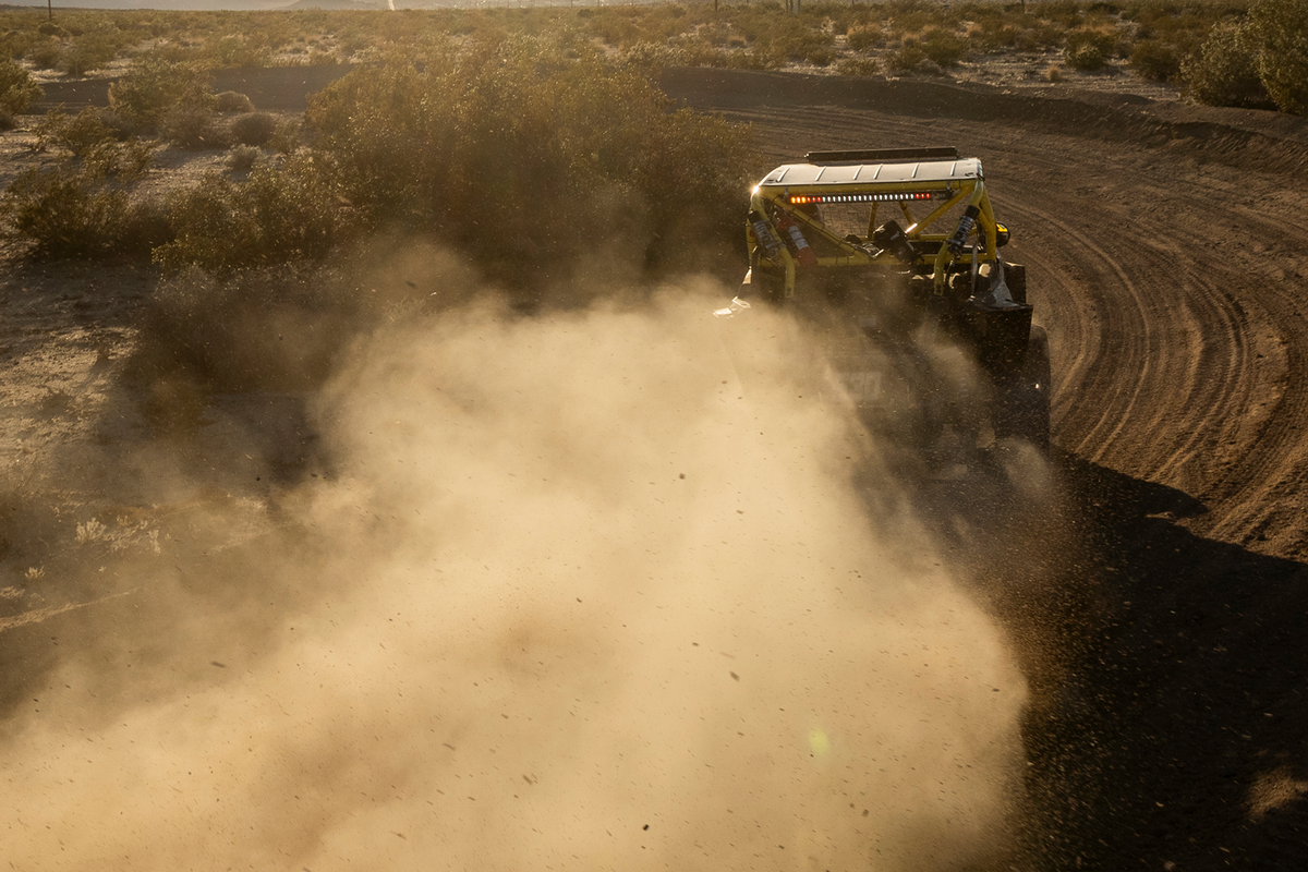 Off-road vehicle driving on a dirt track kicking up dust